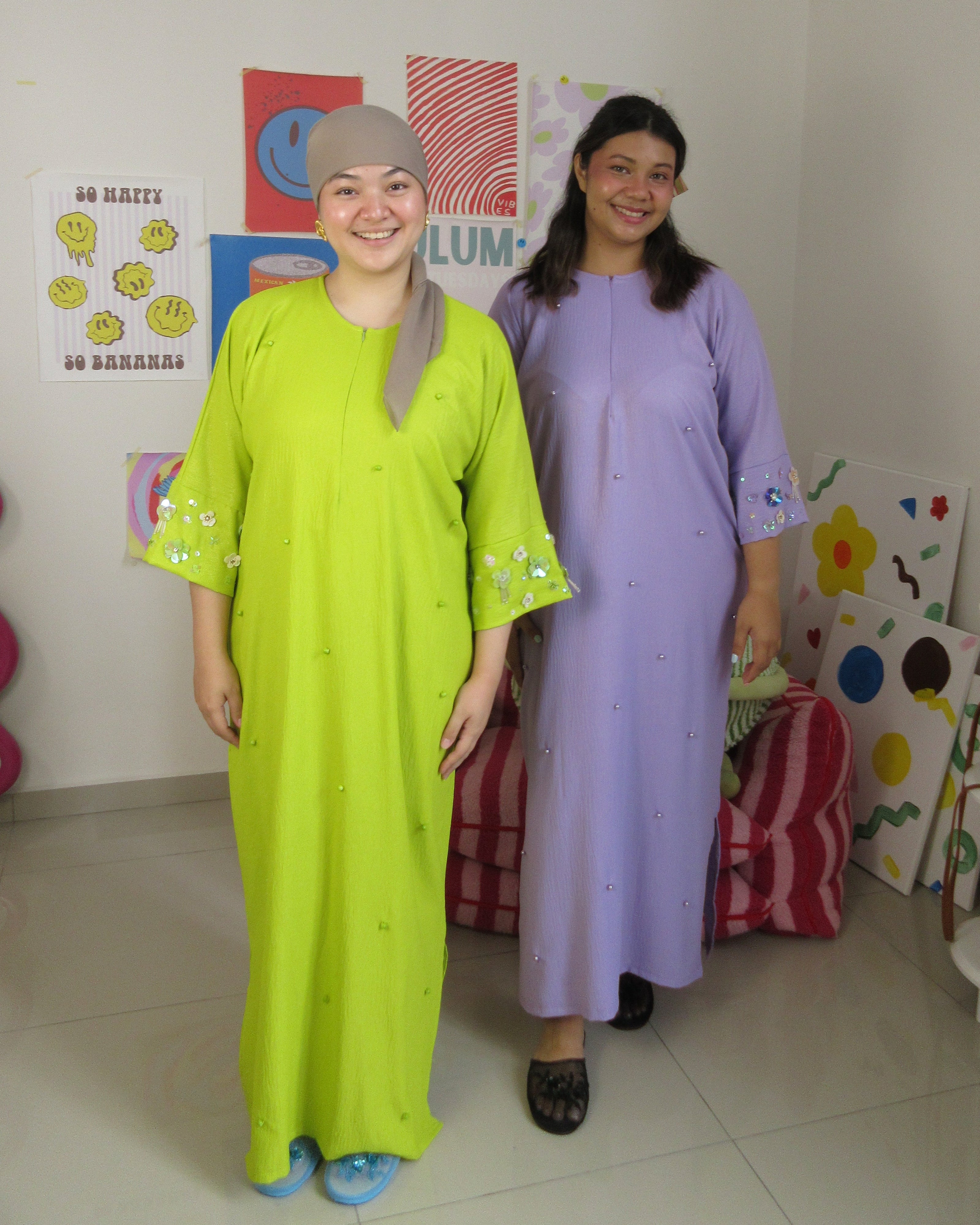 Two women standing in a room with colorful decorations on the wall wearing Malaysia's best slow fashion local brand Flair