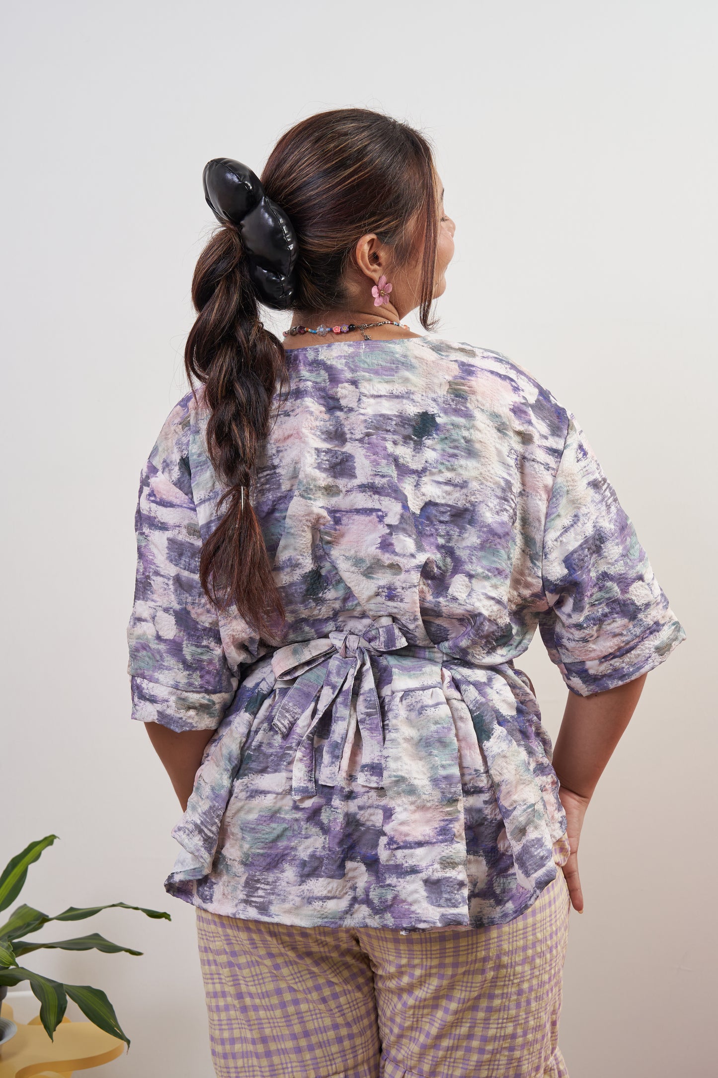 Back view of Liliana Top in Wisteria with ribbon tied at the back, showcasing adjustable fit and soft purple peplum style with ruffled hem