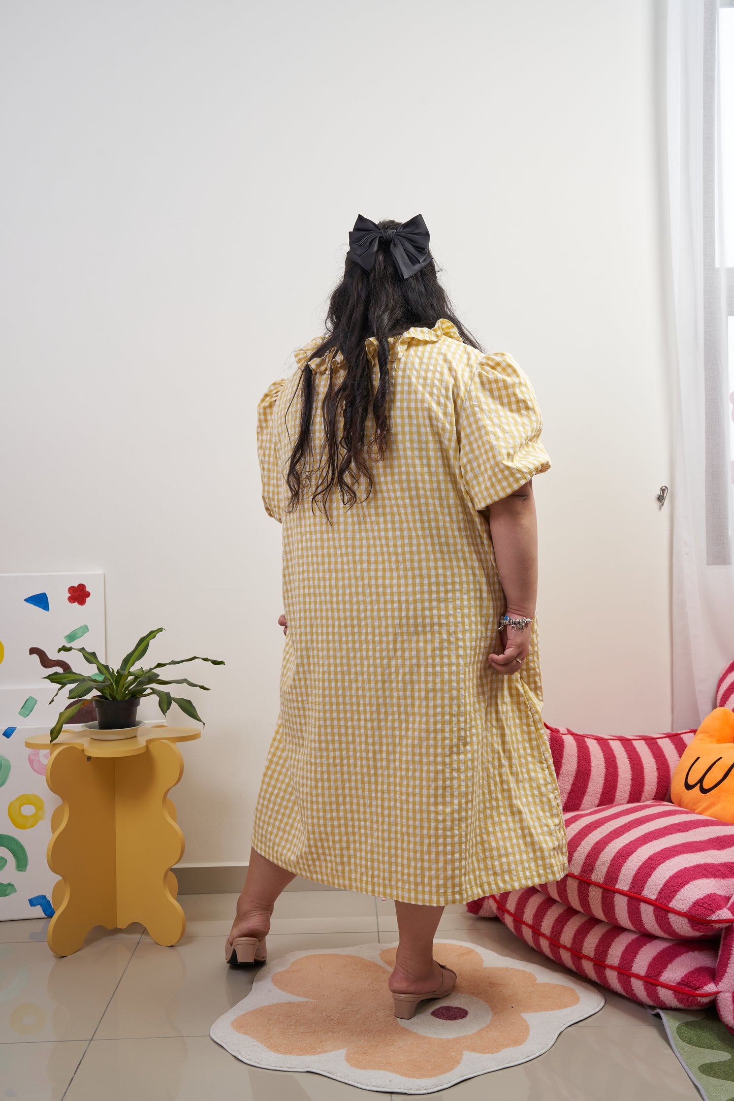 Full-length back view of Bea Dress in Sunny Gingham, featuring adjustable ruffled neckline, yellow gingham print, and relaxed trapeze silhouette.