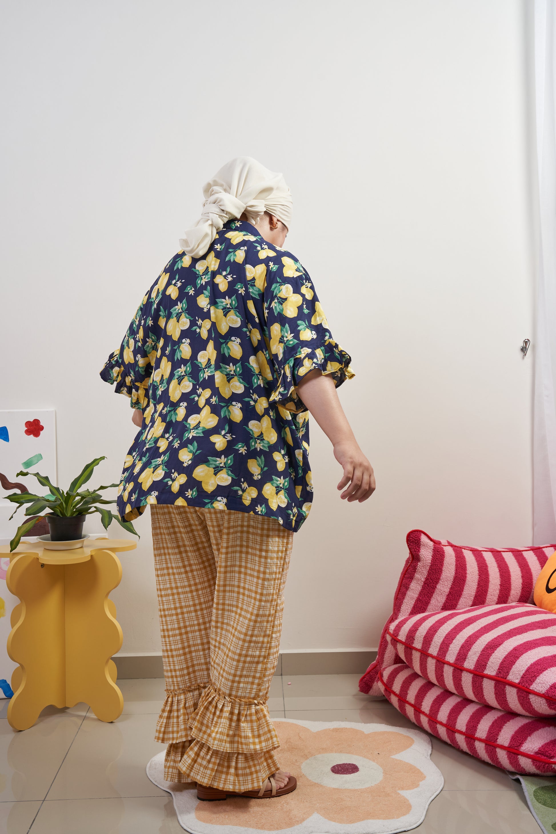 Back view of Buttoned Belle Blouse in Lemon Dream, highlighting the flowy, loose fit with a modest silhouette, styled with Flutter Flair Pants in Lemonade