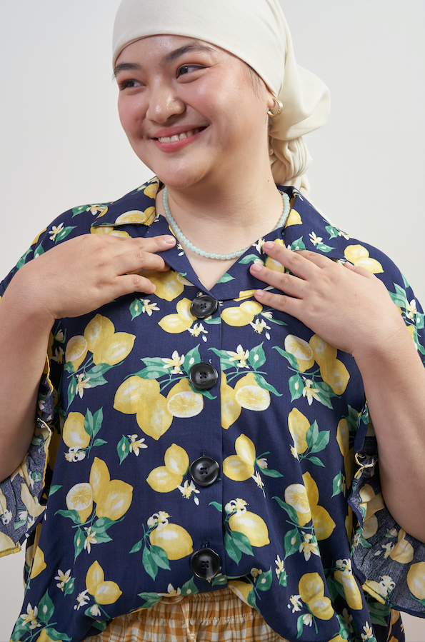 Close-up of Buttoned Belle Blouse in Lemon Dream, highlighting vintage buttons and collared neckline with lemon print on dark blue base.
