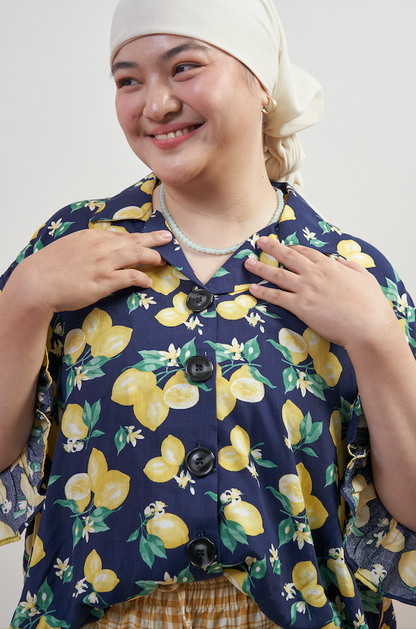 Close-up of Buttoned Belle Blouse in Lemon Dream, highlighting vintage buttons and collared neckline with lemon print on dark blue base.