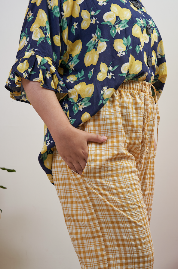 Side view of Flutter Flair Pants in Lemonade, semi close-up with hands in pockets, showing side seam pocket and loose fit.