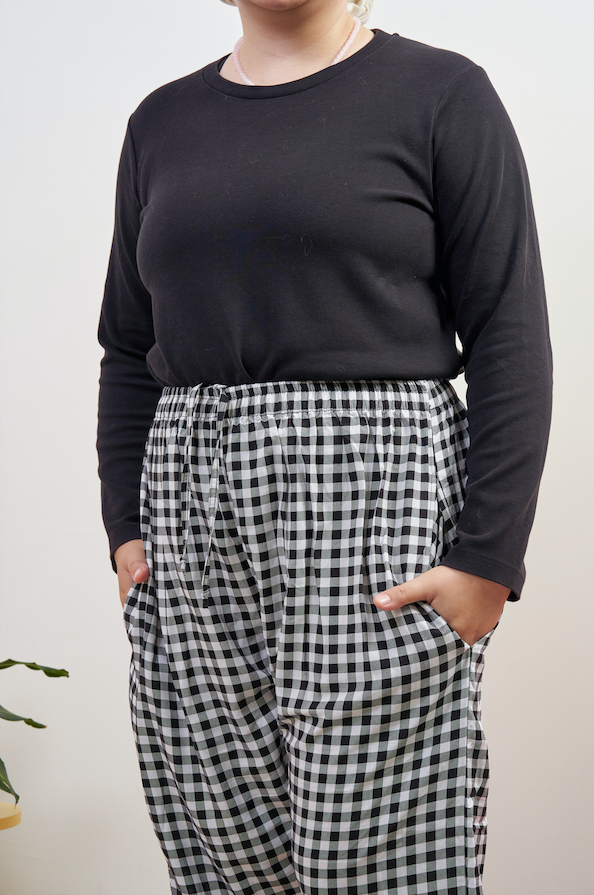 Close-up of Flutter Flair Pants in Noir Blanc, model with both hands in side pockets, highlighting black & white gingham pattern and loose fit.