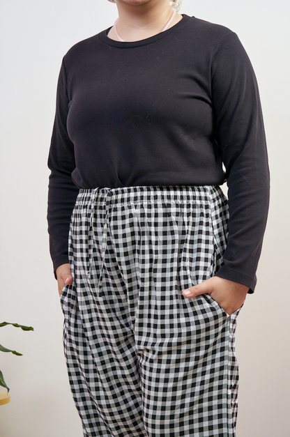 Close-up of Flutter Flair Pants in Noir Blanc, model with both hands in side pockets, highlighting black & white gingham pattern and loose fit.