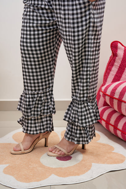 Close-up of lower section of Flutter Flair Pants in Noir Blanc, showcasing double ruffle hem detail in black & white gingham pattern