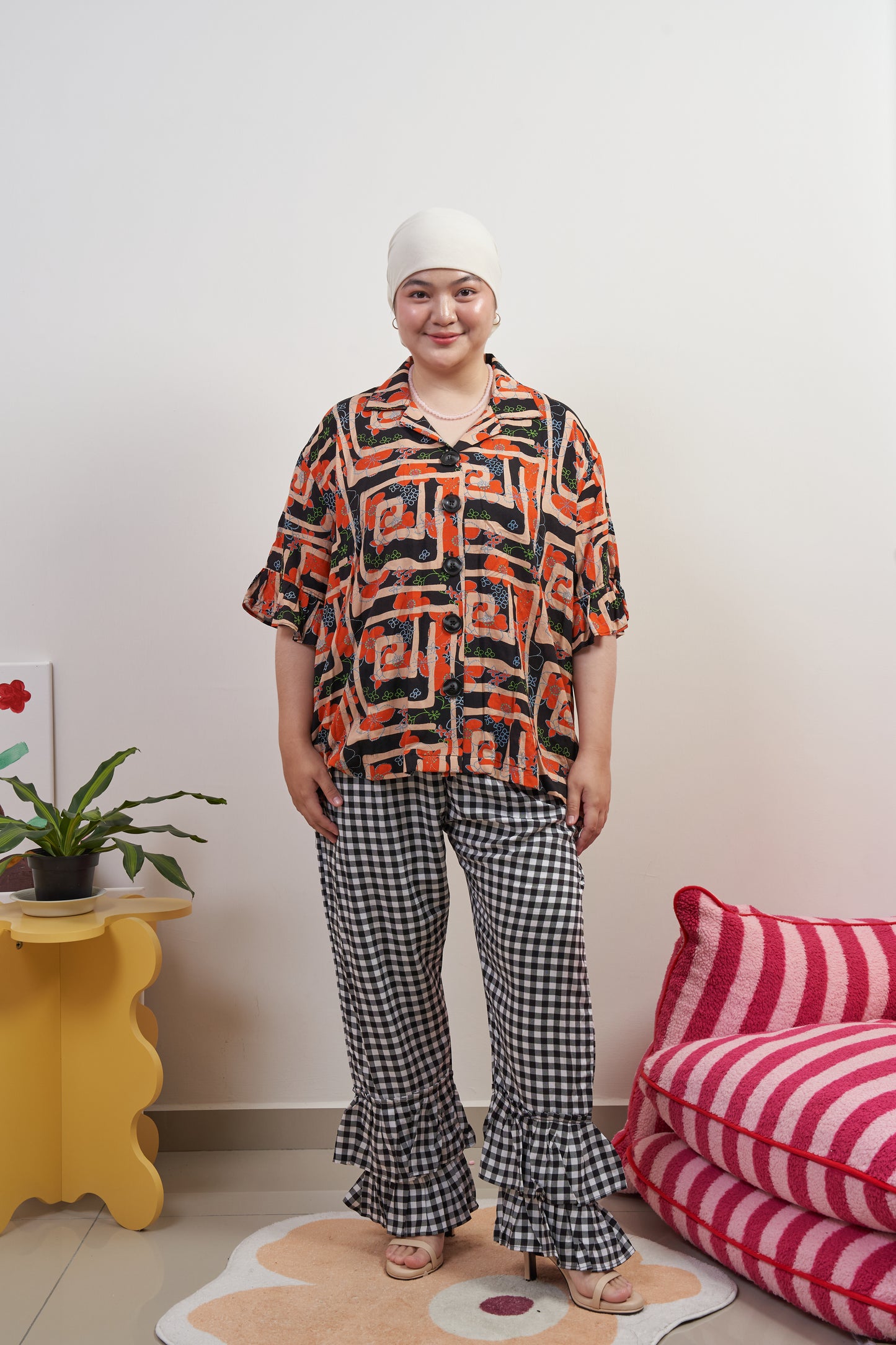 Full frontal view of Flutter Flair Pants in Noir Blanc styled with Buttoned Belle Blouse in Abstract Garden, untucked to highlight loose fit, double ruffle hem, and gingham pattern.