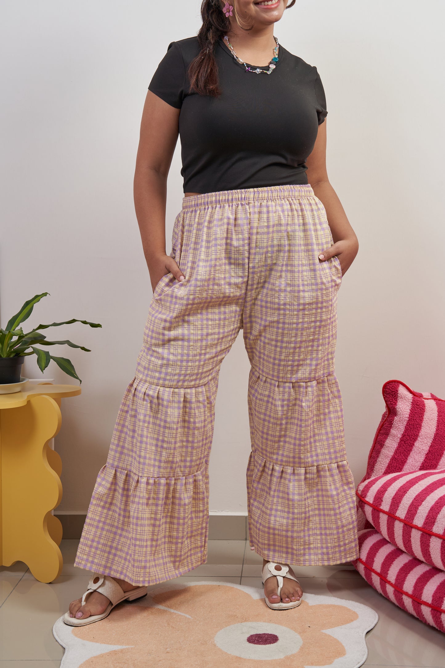 Front profile of Flutter Tier Pants in Orchid Zest, showing purple and yellow plaid pattern, double-tier ruffled flared hem, and loose fit.