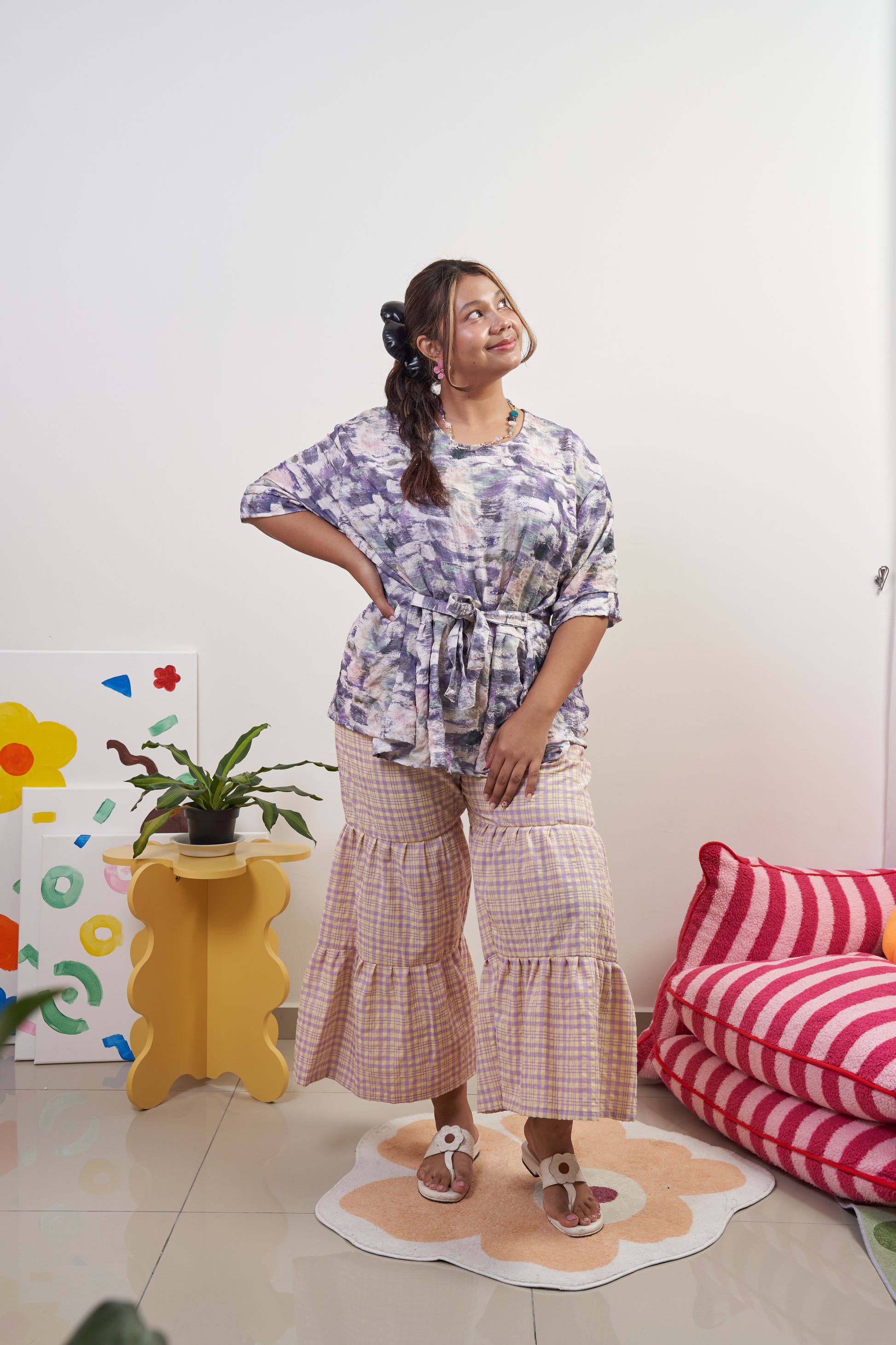 Full-body angled view of Liliana Top in Wisteria with ribbon tied at the front, paired with Flutter Tier Pants in Orchid Zest, showing relaxed, breezy fit and peplum style.