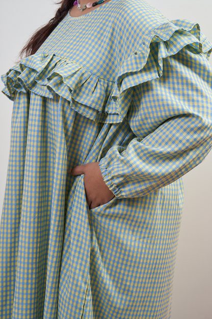Close-up side view of Rhea Dress in Felicia Daisy, showcasing the ruffle detail and side pocket, with yellow and blue gingham print